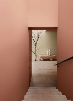 an open door leading to a room with pink walls and white vases on the steps