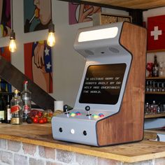 an old fashioned video game sitting on top of a wooden counter next to bottles and glasses