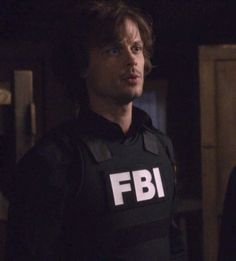 a man in a black shirt with the word fbi on his chest standing next to another man