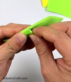 two hands are holding a green piece of paper