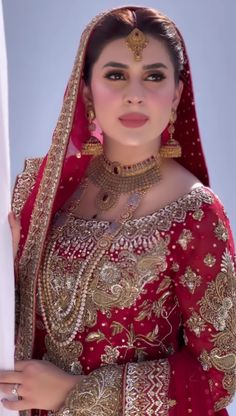 a woman wearing a red and gold bridal outfit