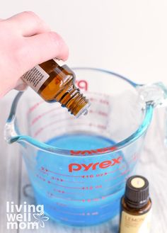 a hand pouring blue liquid into a measuring cup with an orange and white label on it