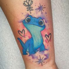 a small blue frog tattoo on the right leg with hearts and stars in the background