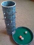 a cup with two dices sitting on top of it next to a game table