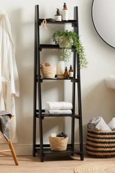 a shelf with towels, plants and other items in it next to a mirror on the wall