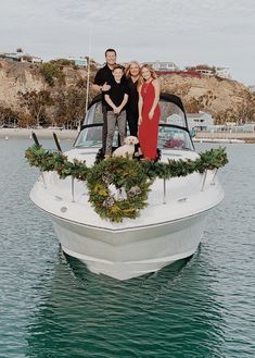 three people standing on the bow of a boat with wreaths hanging from it's side