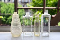 three empty glass bottles sitting on top of a window sill next to each other