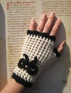 a woman's hand wearing a white and black knitted glove with an animal on it