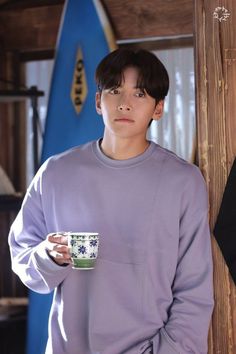 a young man is holding a coffee cup