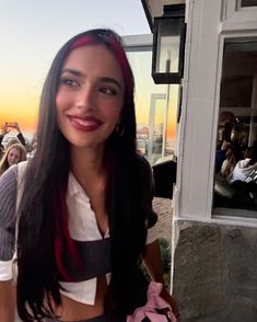 a woman standing in front of a building with her hair pulled back and smiling at the camera