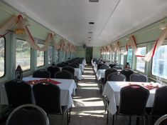 the inside of a train car with tables and chairs set up for formal dining,