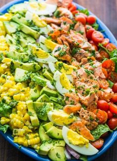 a blue bowl filled with salad on top of a wooden table