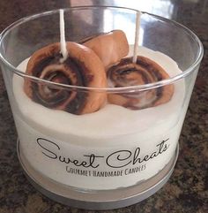 a candle with cinnamon buns in it sitting on a counter