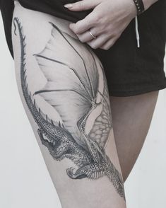 a woman's thigh with a dragon tattoo on it and the leg is black and white