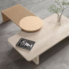 a wooden table with a book on it next to a vase and a small plant