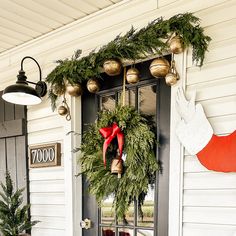 a christmas wreath on the front door of a house with bells and stockings hanging from it