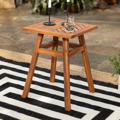 an outdoor table with two candles on it and a black and white rug in the background