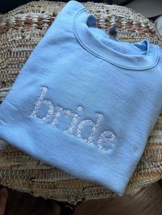 a blue shirt with the word bride on it sitting on top of a wicker chair