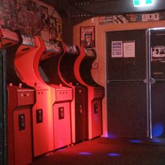 a row of vending machines sitting next to each other in a room with posters on the wall