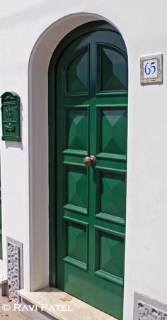 a green door is shown in front of a white building with an arched entryway