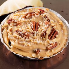 a pie with pecans and caramel drizzled on top sitting on a table