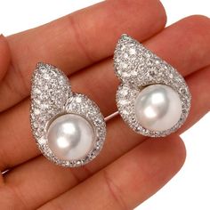 These elegant 1980's diamond and pearl tear drop shaped clip on earrings are crafted in solid 18 karat white gold, weighing 23.6 grams and measuring 30mm x 20mm. Showcasing a pair of prominent lustrous cultured pearls in white creamy color and measuring 13mm in diameter, one with very few natural inclusions. Surrounded by a tear drop shape frame pave-set with 130 round cut diamonds, collectively weighing approximately, 7.50 carats, graded G-H color, and VS1-VS2 clarity. Feature a filigree design Luxury Drop Pearl Earrings For Formal Occasions, Luxury Drop Pearl Earrings For Formal Events, Teardrop Diamond Pearl Earrings For Evening, Diamond Pearl Drop Earrings For Anniversary, White Gold Diamond Pear Shaped Pearl Earrings, Anniversary Diamond Pearl Drop Earrings, Anniversary Drop Pearl Earrings With Diamonds, Formal Pear Shaped Diamond Pearl Earrings, Anniversary White Gold Drop Pearl Earrings