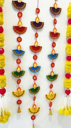 an assortment of colorful decorations hanging on a white wall with red and yellow pom poms