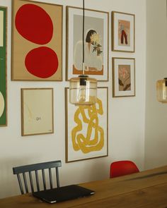 a dining room table with chairs and pictures on the wall above it, along with a laptop computer