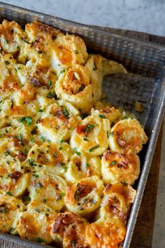 a casserole dish in a metal pan with cheese and herbs on the side