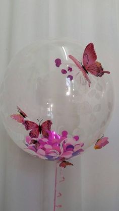 the balloon is filled with pink butterflies and streamers on it's side,