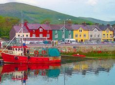 a red boat sitting in the middle of a body of water next to some houses