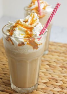 two glasses filled with ice cream and caramel on top of a wicker table