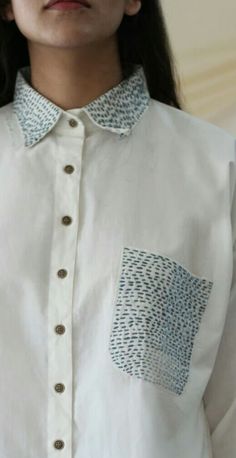 a close up of a person wearing a white shirt with blue and black designs on it