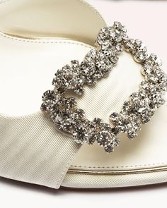 a pair of white shoes with bows on the side and crystal brooch in the middle