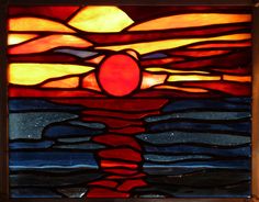 a stained glass window with an image of the sun rising in the sky over water