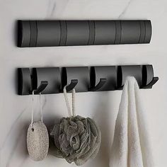 three black hooks on the wall with towels hanging from them