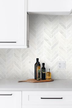 a kitchen with white cabinets and tile backsplash, including bottles on the counter