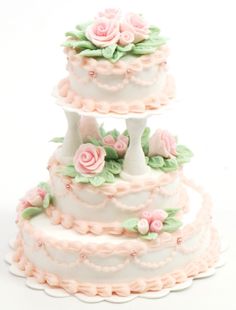 three tiered wedding cake with pink roses on top and green leaves around the edges