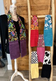 several colorful towels are hanging on a wooden rack next to a white mannequin