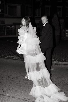 black and white photograph of bride and groom walking down the street at night in tuxedo