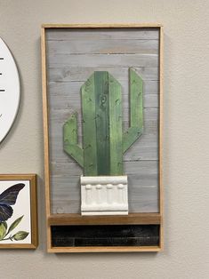 a green cactus in a wooden frame on the wall