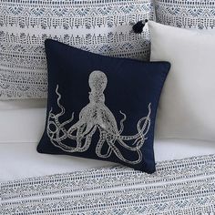 an octopus pillow sitting on top of a bed next to two white pillows with black trim