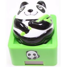 a panda bear toy sitting on top of a green box with toothbrushes in it