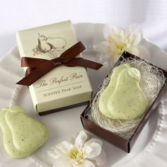 a white plate topped with two pears next to a box of soap and flowers