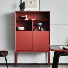 a red cabinet sitting in the corner of a room next to two chairs and a table