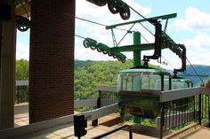 a green cable car sitting on the side of a building