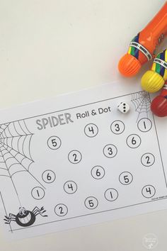 a spider roll and dot game next to some crayons on a white table