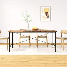 a dining room table with chairs and a bowl of fruit on the top, in front of a white wall