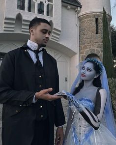 a man and woman dressed up as corpse bride and groom in front of a castle