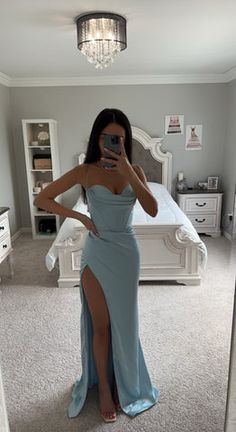 a woman taking a selfie in her bedroom wearing a blue dress and high heels